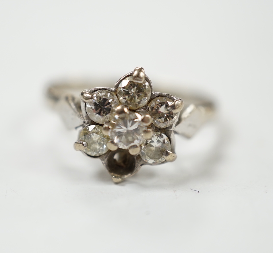 An 18ct white metal and seven stone diamond cluster set flower head ring (one stone missing), size K/L, gross weight 3.4 grams.